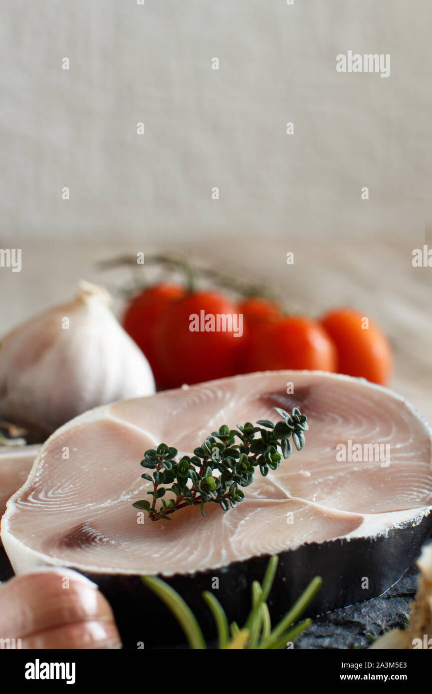 Shark steak on a wooden board with vegetables and herbs Stock Photo