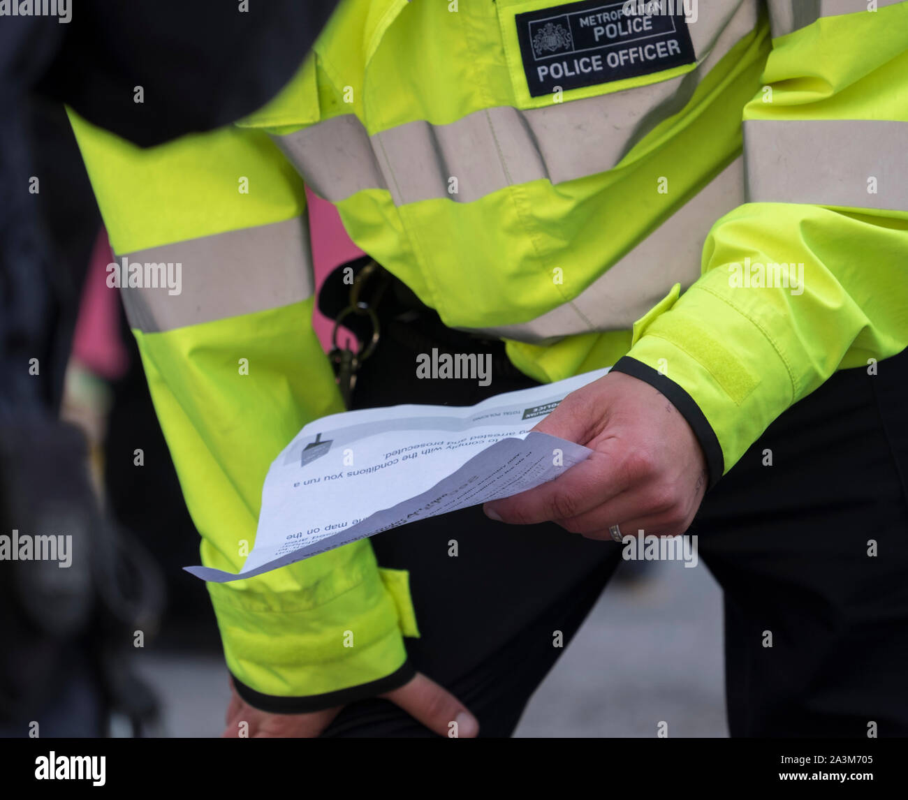 Whitehall, London, UK. 9th October 2019. Large police presence makes arrests and removes Extinction Rebellion activists who have glued themselves to Whitehall. Officer reads a Section 14 Public Order Act notice to two demonstrators on the road. Credit: Malcolm Park/Alamy Live News. Stock Photo