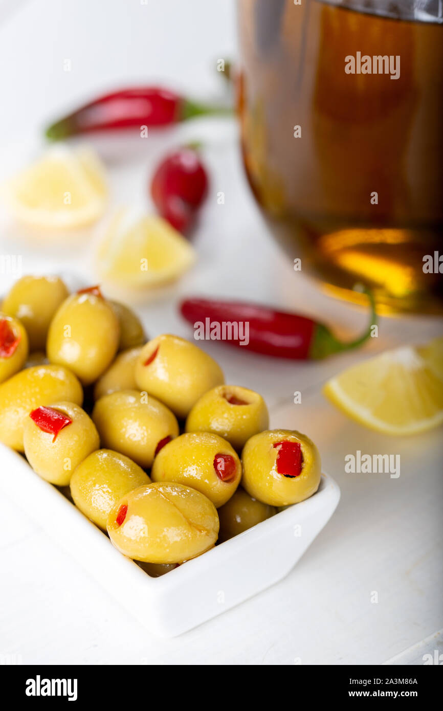 Bowl of green olives stuffed with red pepper on white background Stock