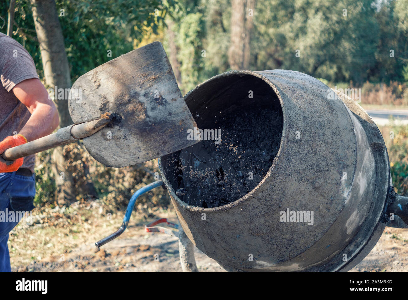 Builder preparing fresh concrete in a cement mixer adding components