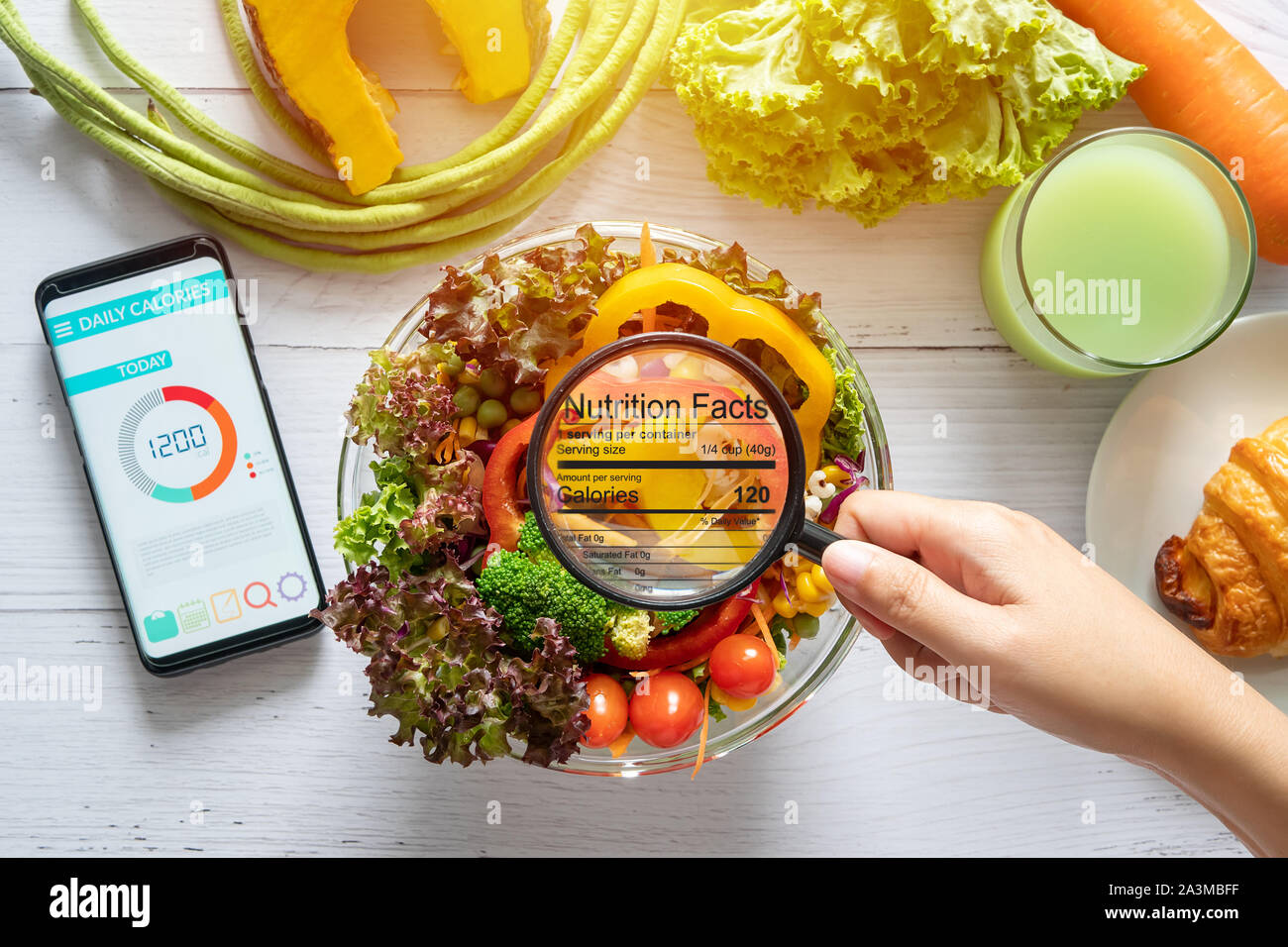 nutritional information concept. hand use the magnifying glass to zoom in to see the details of the nutrition facts from food , salad bowl Stock Photo