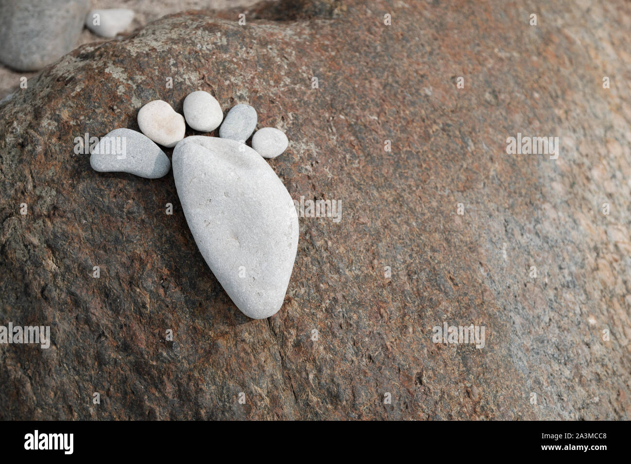 A footprint composed of six flat stones placed on a rock stone on the Baltic Sea. Stock Photo