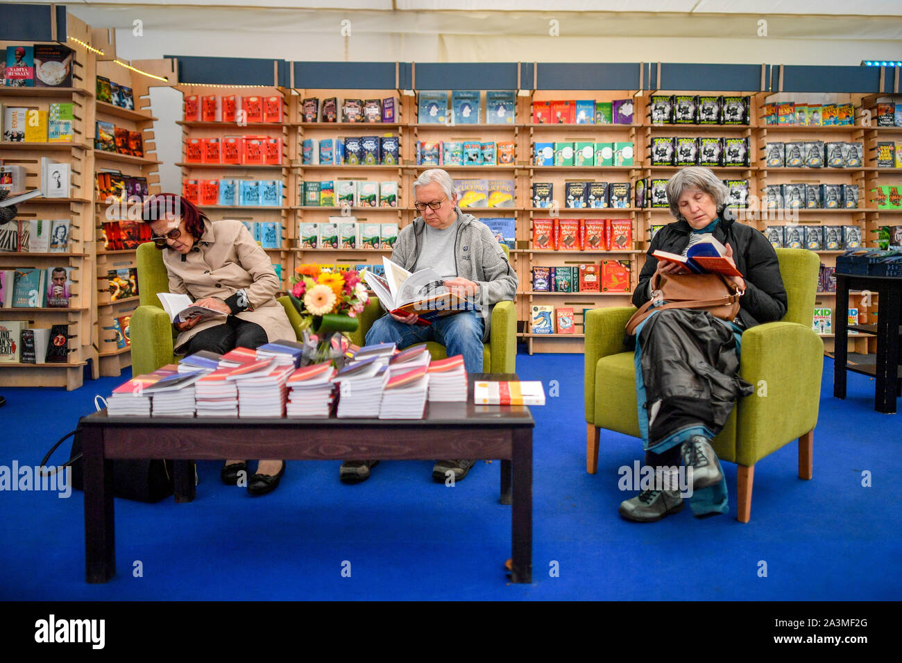 People sit and read books in a bookstore at Cheltenham Literature Festival, the longest running Literature Festival in the world which is celebrating its 70th year. Stock Photo