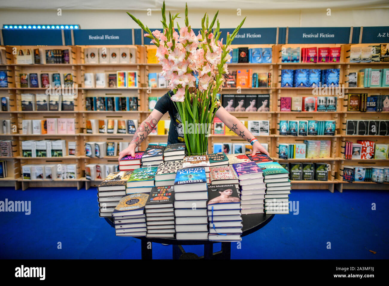 A worker organises and straightens books in a bookstore at Cheltenham Literature Festival, the longest running Literature Festival in the world which is celebrating its 70th year. Stock Photo
