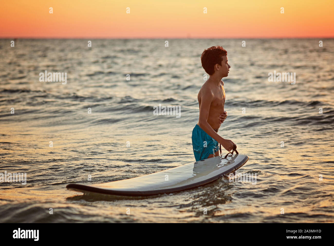 Guy surfer walking with surfboard at sunset in israel Stock Photo Alamy