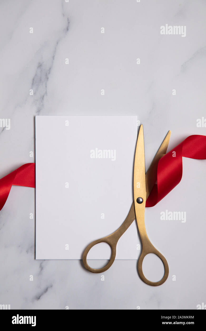 Grand opening background. Gold scissors with red ribbon on a marble