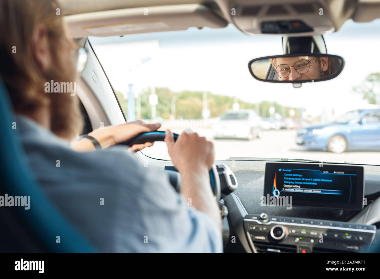 Young adult man sitting in car, looking at rear view mirror Stock Photo ...