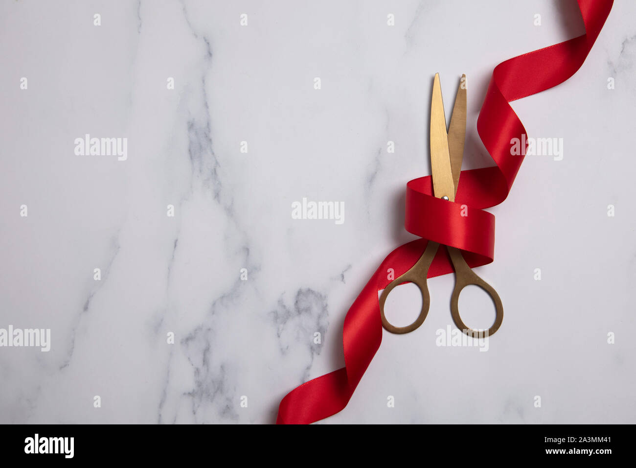 Grand opening background. Gold scissors with red ribbon on a marble