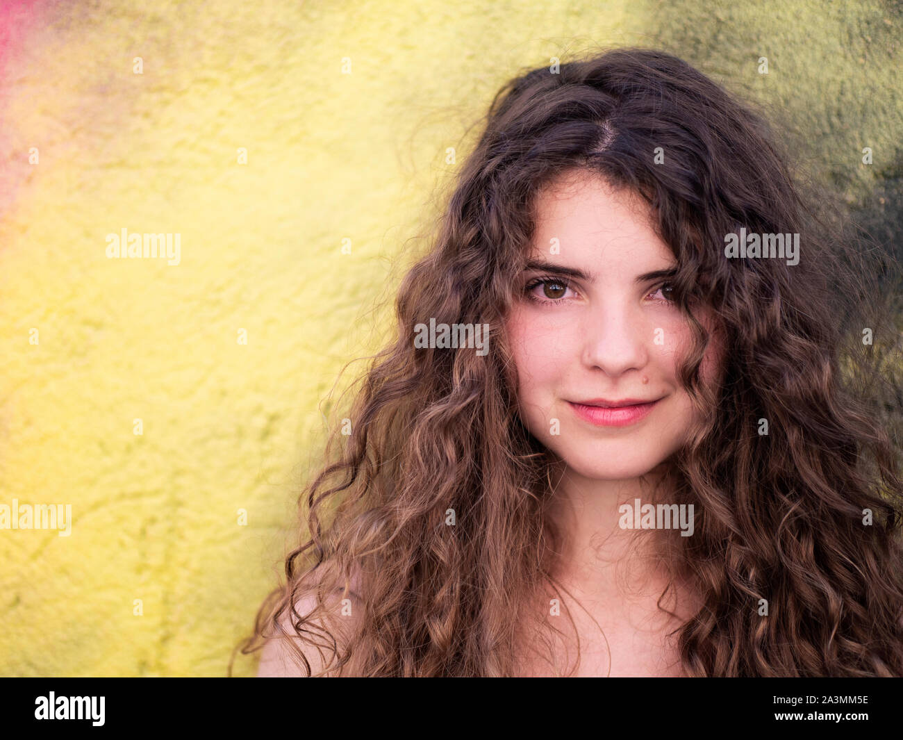 Beautiful young woman against colorful wall Stock Photo