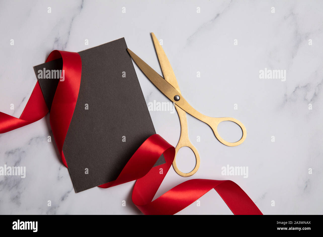 Grand opening background. Gold scissors with red ribbon on a marble