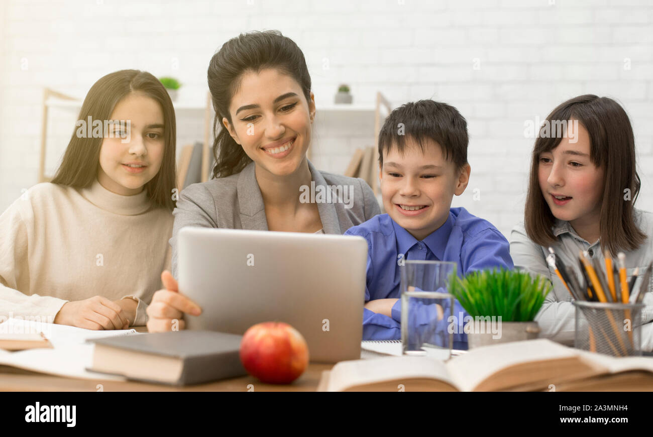 Children and female teacher looking on tablet at lesson Stock Photo