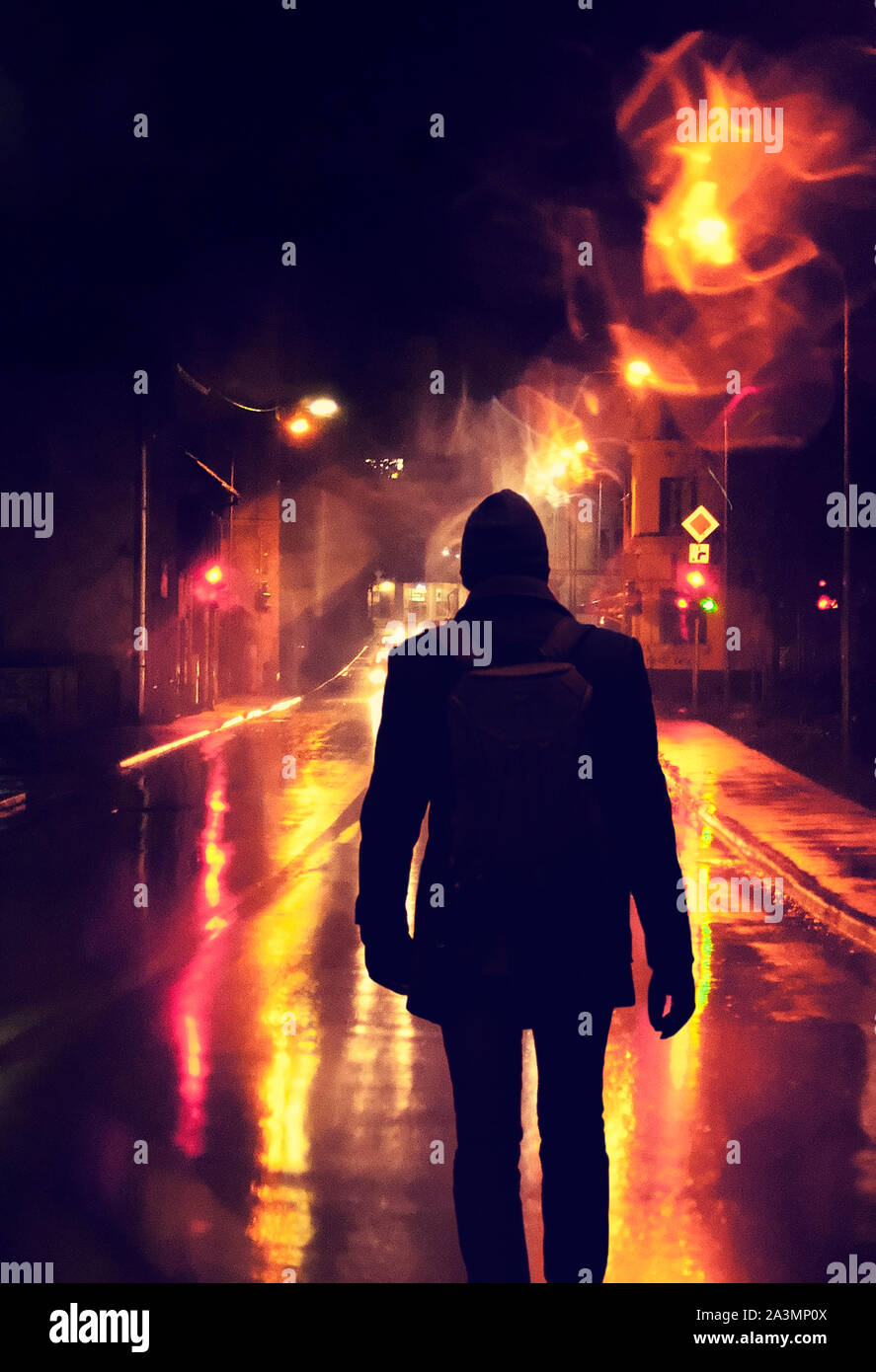 silhouette of a young man walking down wet road on a rainy night Stock ...