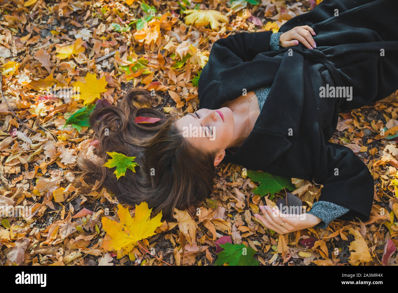 woman laying on the ground in autumn yellow leaves Stock Photo - Alamy