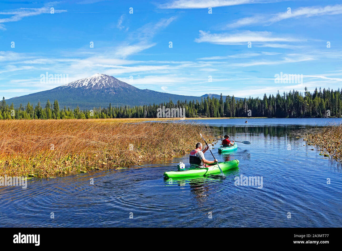 Kayakers on Hosmer Lake in the Oregon Cascade Mountains in early autumn. Mount Bachelor is in the background. Stock Photo