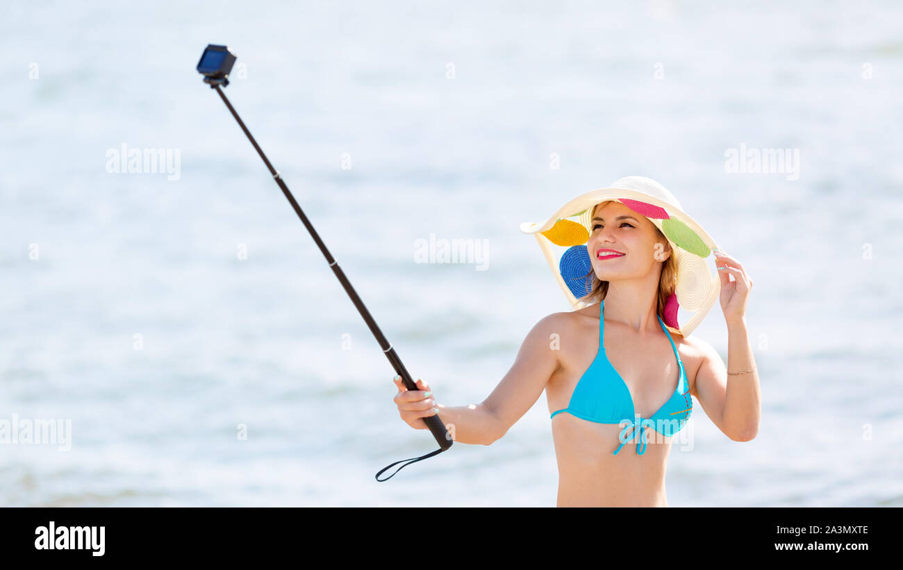 A woman in a hat and bikini is filming a vacation video Stock Photo - Alamy