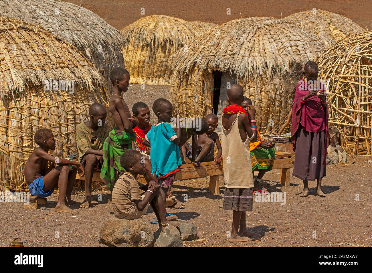 Boys and girls from the El Molo tribe playing near their typical huts made of straw on their village on the shores of Lake Turkana, Kenya Stock Photo