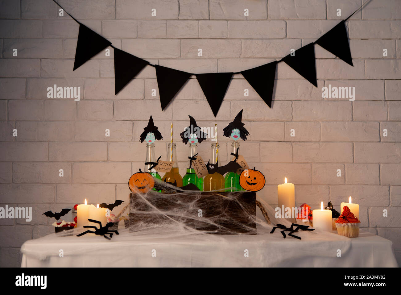 Green witches cocktails and cupcakes over white bricks wall Stock Photo