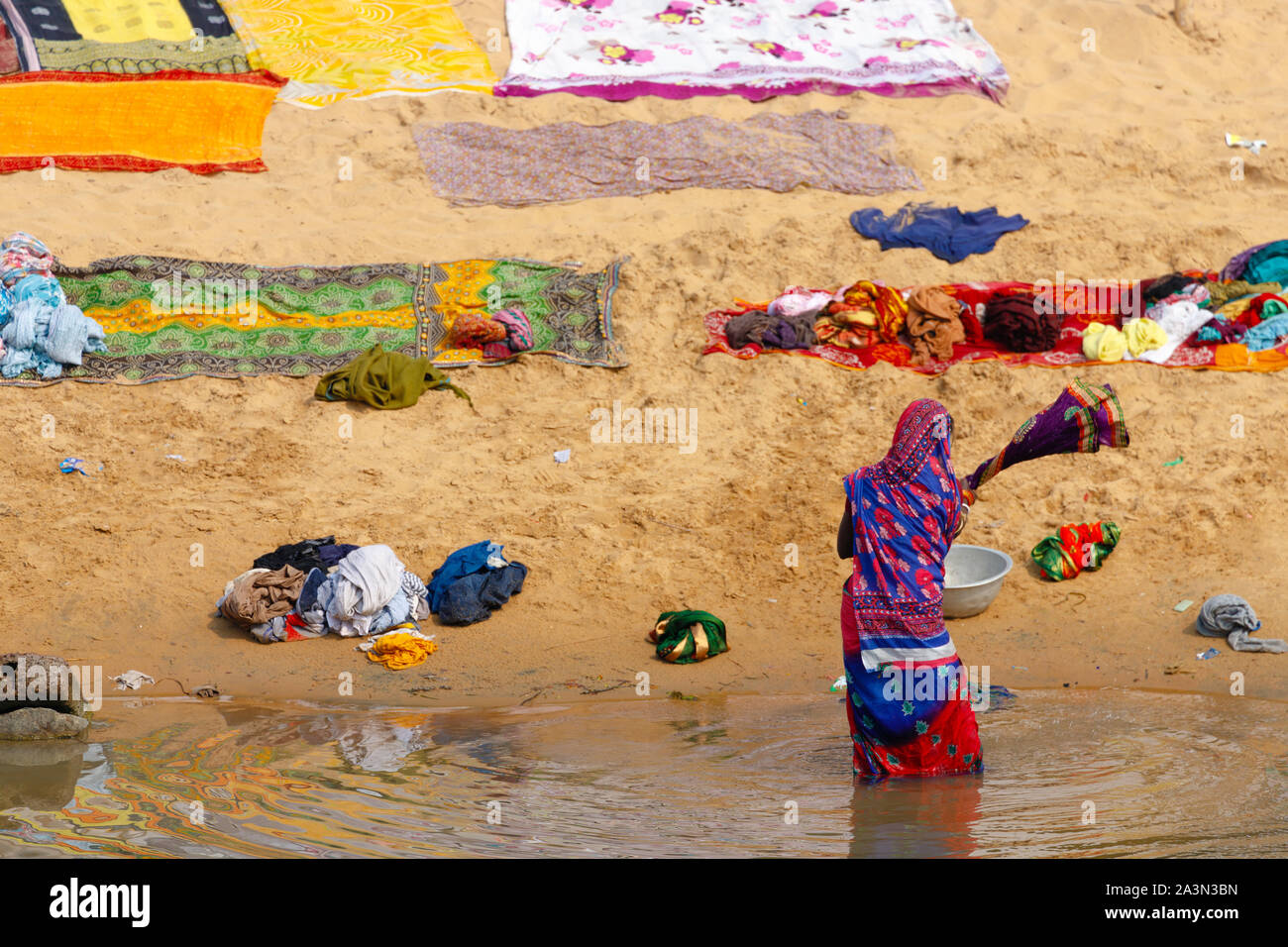 Indian woman washing colorful clothes in the river Stock Photo