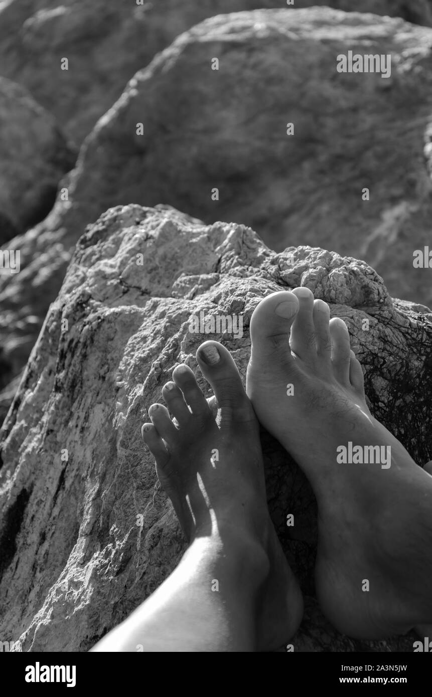 Close up of male and female feet on a stone. Vertical, black and white image Stock Photo