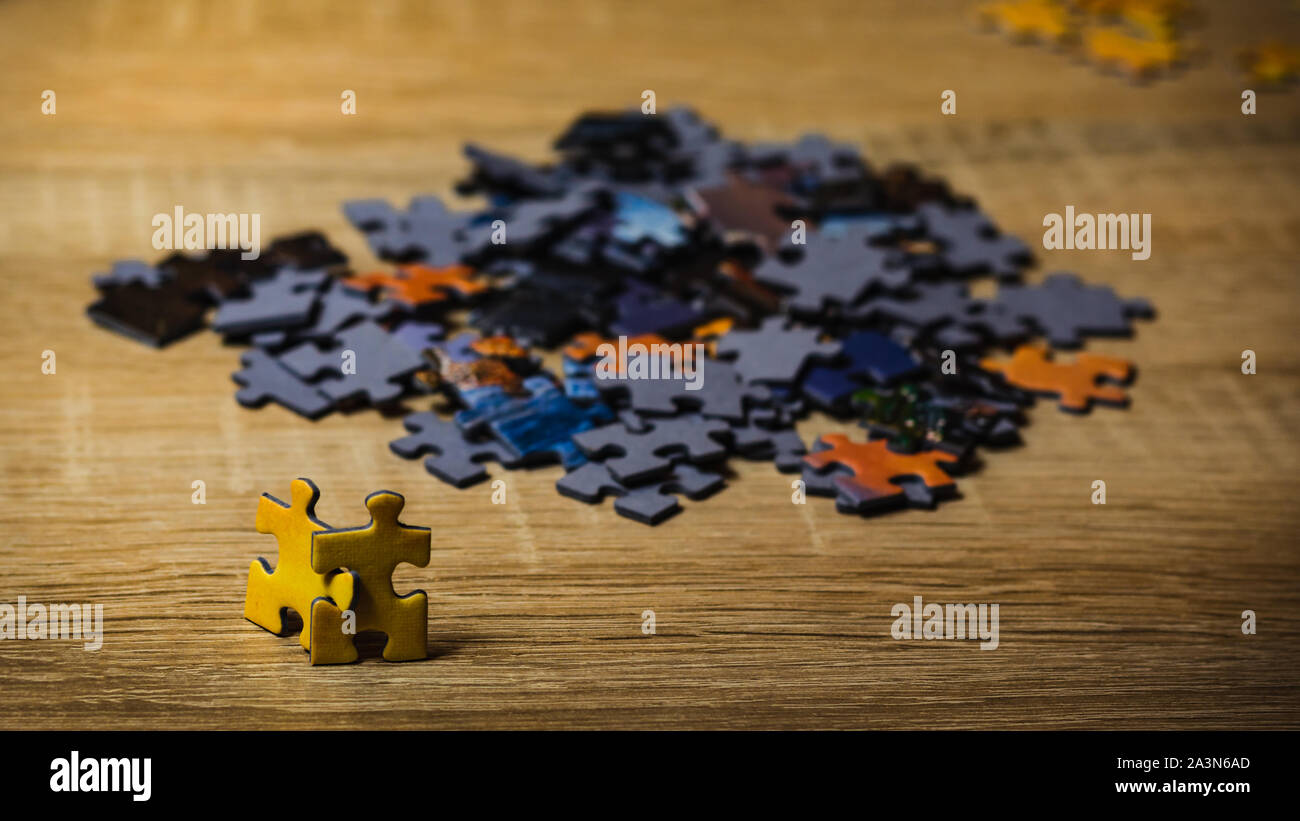 Two yellow puzzles looking at a large group of other puzzles. Concept of attempting to join a group. Stock Photo