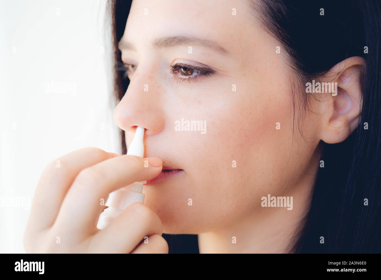 Nasal Spray. Closeup Of Beautiful Young Woman's Face With Nasal Drops. Close-up Of Female Spraying Medical Nasal Spray In Her Nose. Cold And Flu, Heal Stock Photo