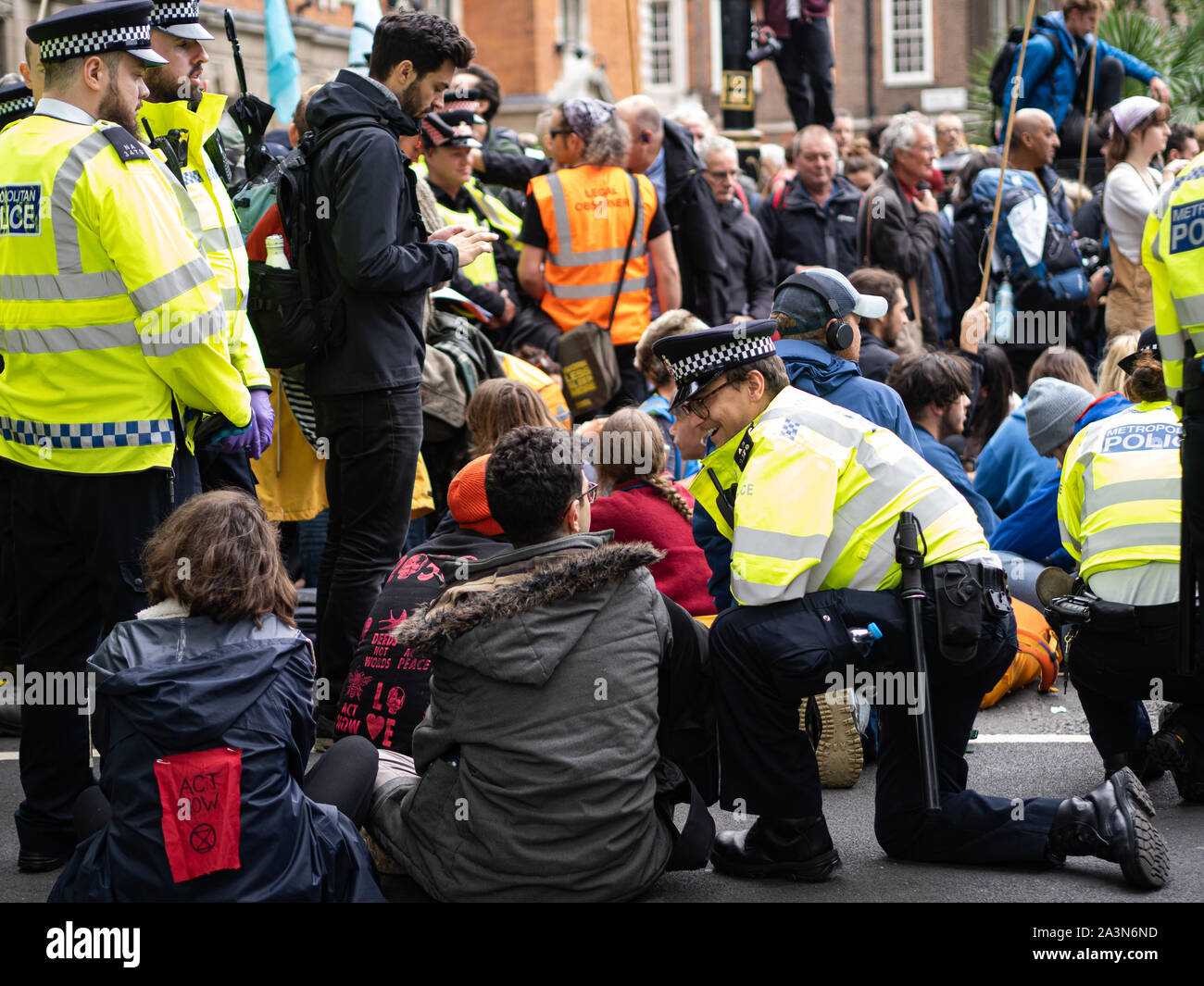 A policeman is smiling while chatting with the Extinction Rebellion demonstrators. Stock Photo