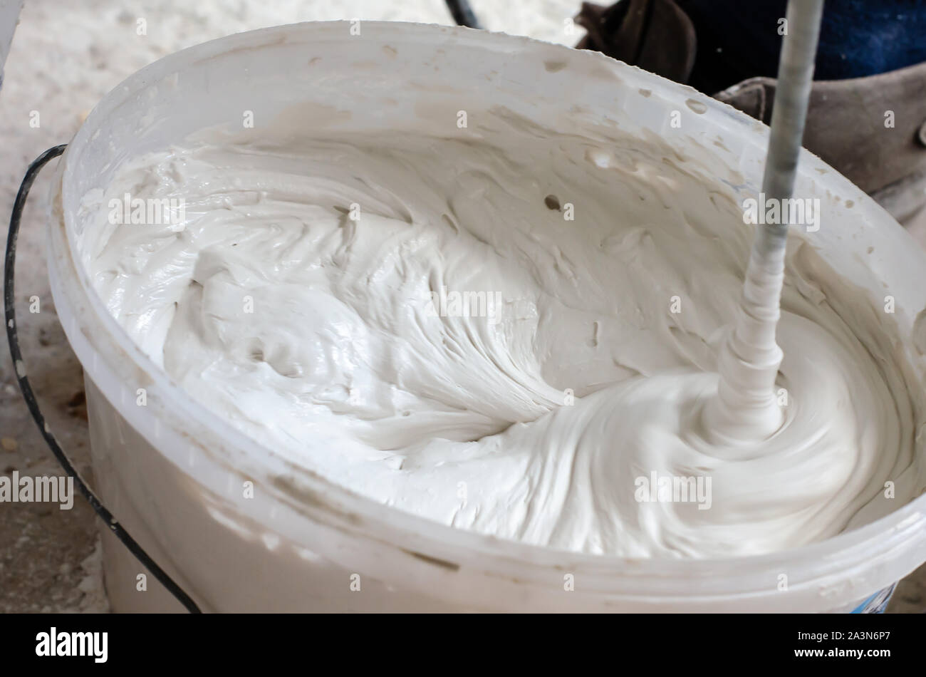 Mixing putty solution in a pail. Construction works concept Stock Photo