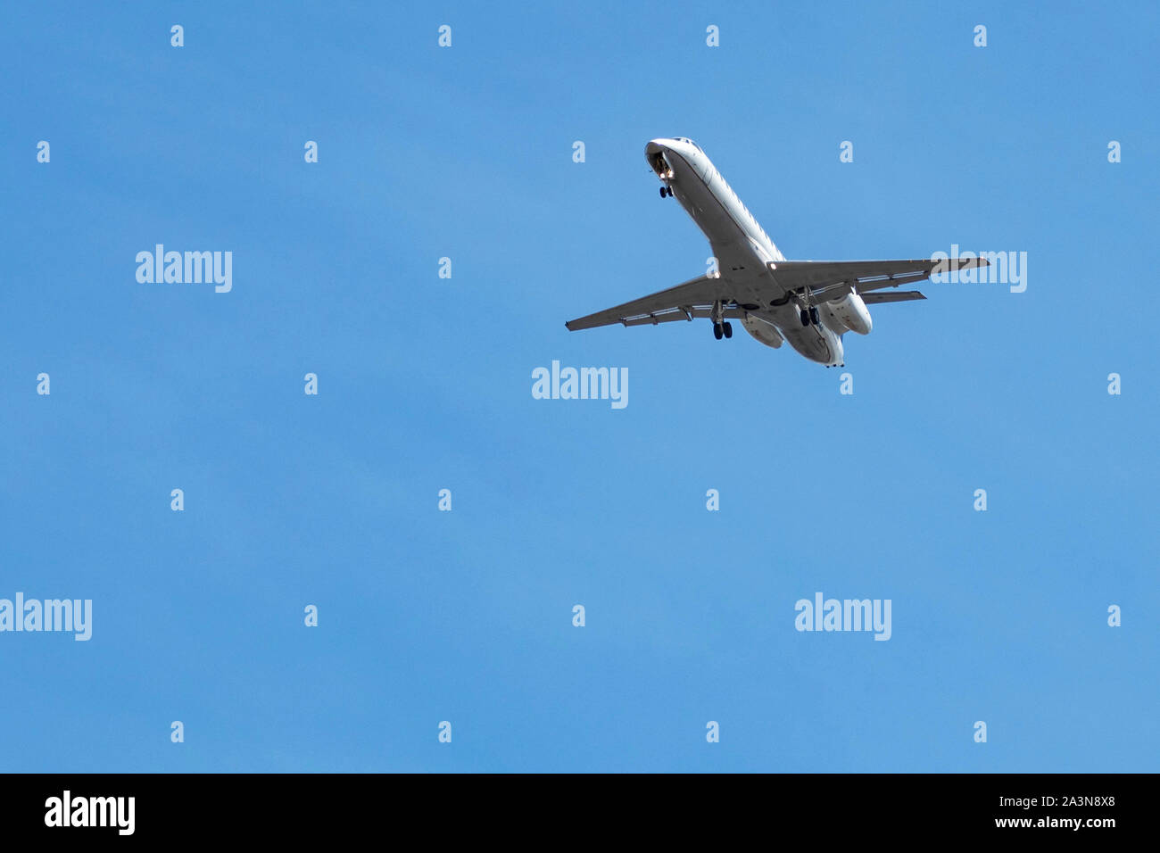 Underside view of Embraer ERJ-145 airplane with landing gear out as it approaches airport for landing Stock Photo