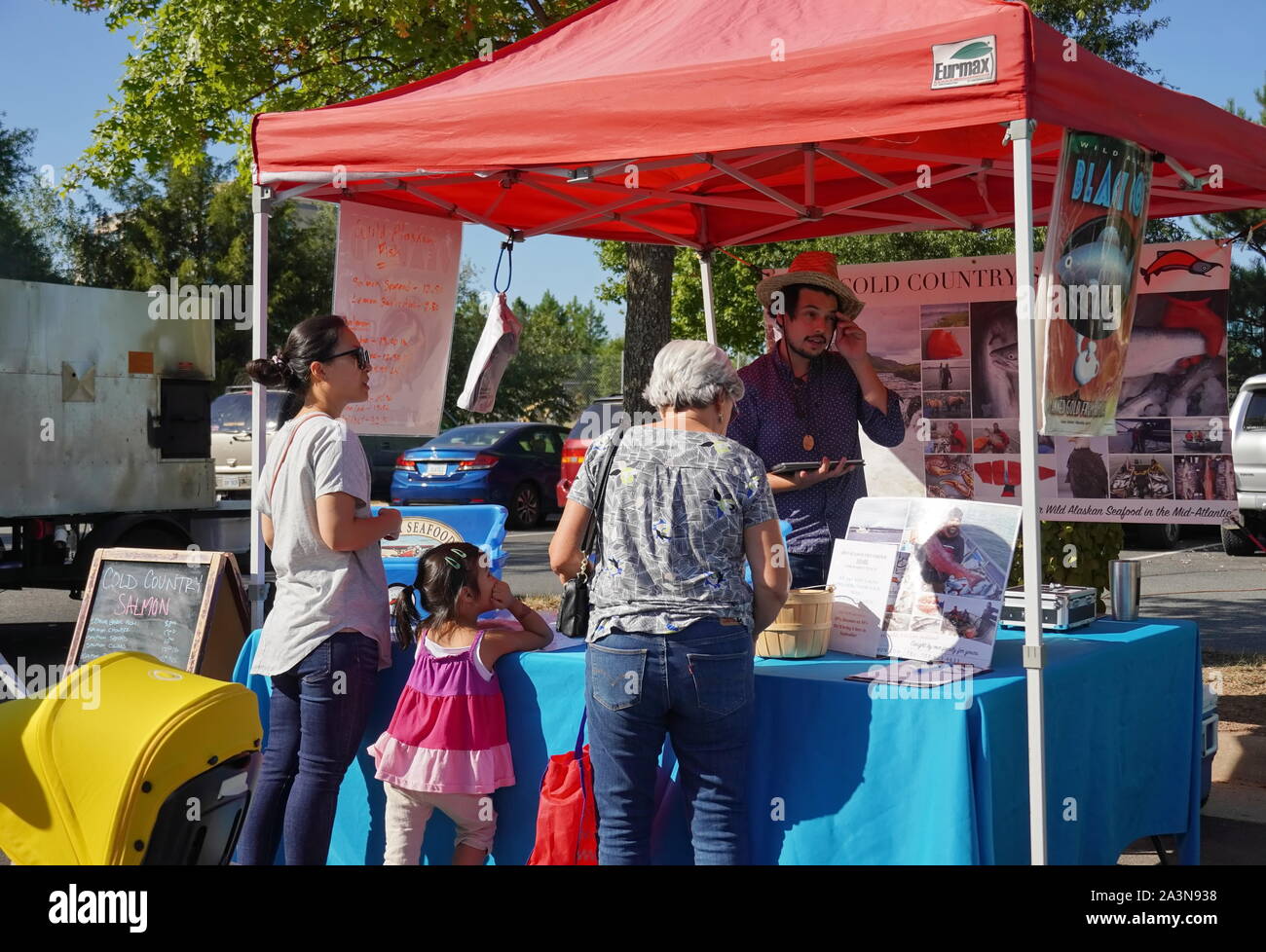 Chantilly, VA / USA - September 19, 2019: Asian family talking to seafood vendor at the Chantilly Community Foodworks Farmers Market Stock Photo