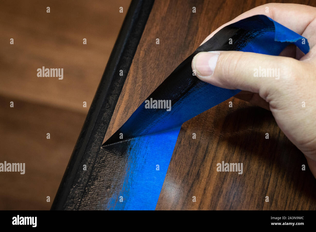 Hand removing blue painter's tape from edge of refinished furniture paint job Stock Photo Alamy