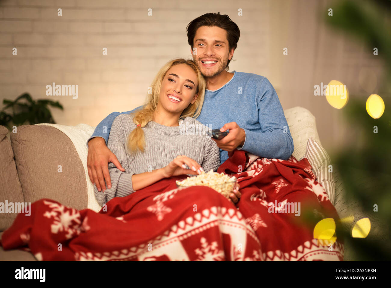 Couple in love at Christmas eve enjoying popcorn Stock Photo