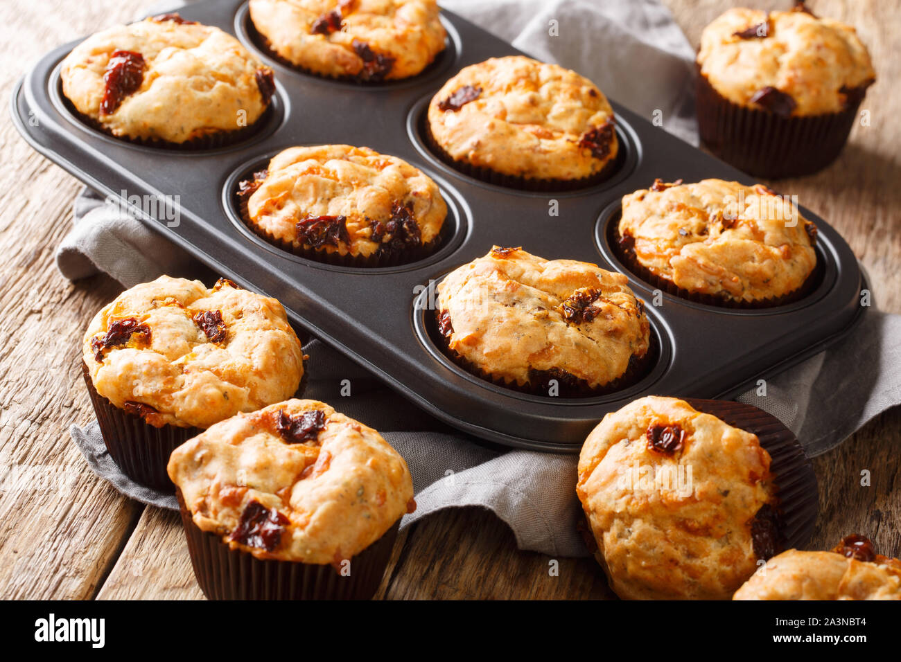 Mediterranean muffins with sun-dried tomatoes and cheddar cheese close-up in a baking dish on the table. horizontal Stock Photo