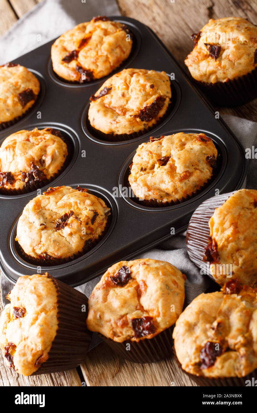 muffins with sun-dried tomatoes and cheddar cheese close-up in a baking dish on the table. vertical Stock Photo