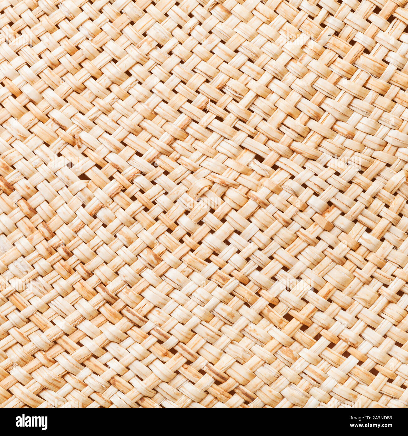 textile square background - texture of summer straw hat from interwoven raffia fibers close up Stock Photo