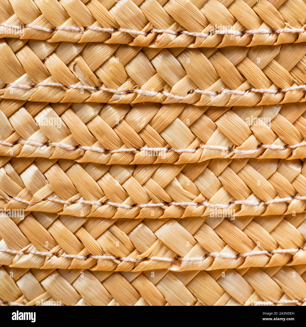 textile square background - texture of stitched summer straw hat from interwoven raffia fibers close up Stock Photo