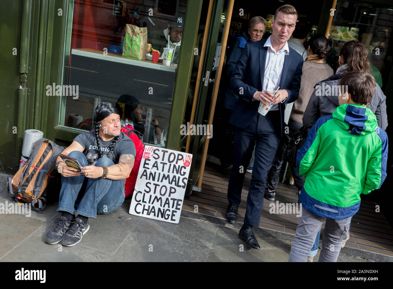 A food science protester sits outside a McDonalds restaurant in Whitehall during the environmental protest about Climate Change occupation of Trafalgar Square in central London, the third day of a two-week prolonged worldwide protest by members of Extinction Rebellion, on 9th October 2019, in London, England. Stock Photo