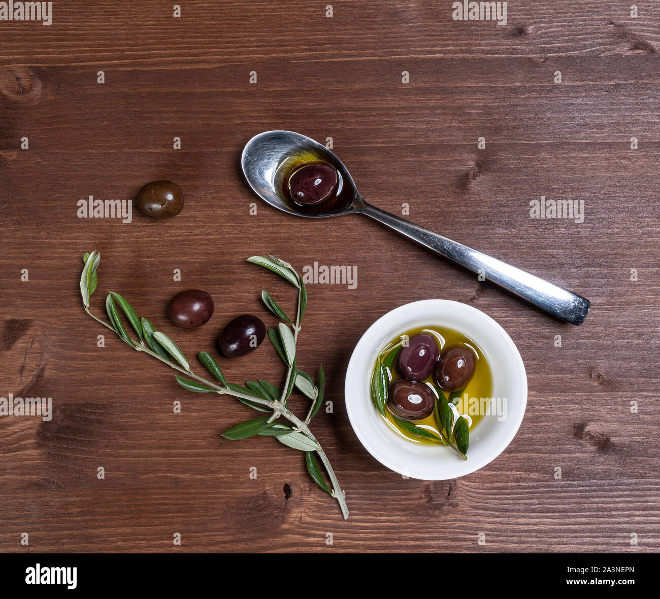 Olive oil and olives on a wooden surface with some Olive branches Stock Photo