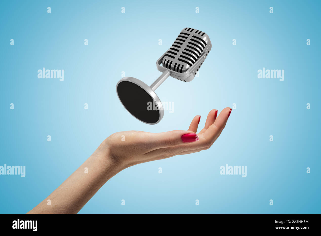 Side closeup of woman's hand facing up and levitating microphone on light blue gradient background. Stock Photo