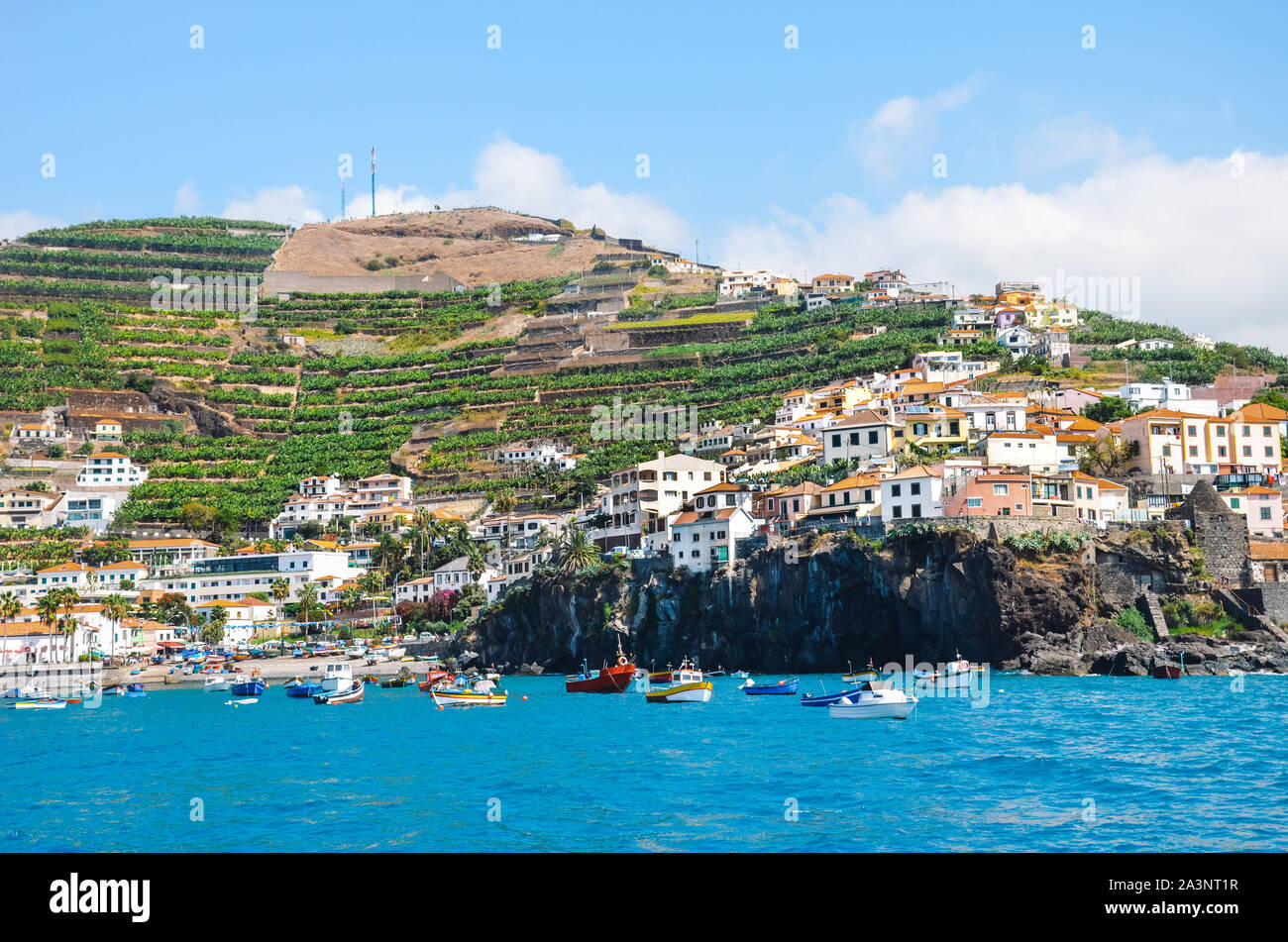 Amazing village Camara de Lobos in Madeira Island, Portugal photographed from the waters of the Atlantic ocean. Small city on a hill by the coast. Tourist destination. Banana plantation on the slope. Stock Photo