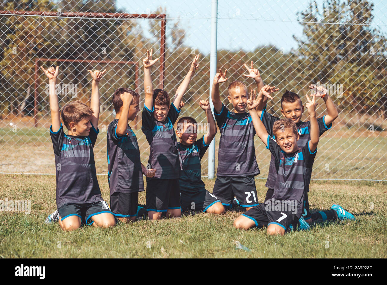 Kids soccer football - young children players celebrating with their hands up, after victory. Stock Photo