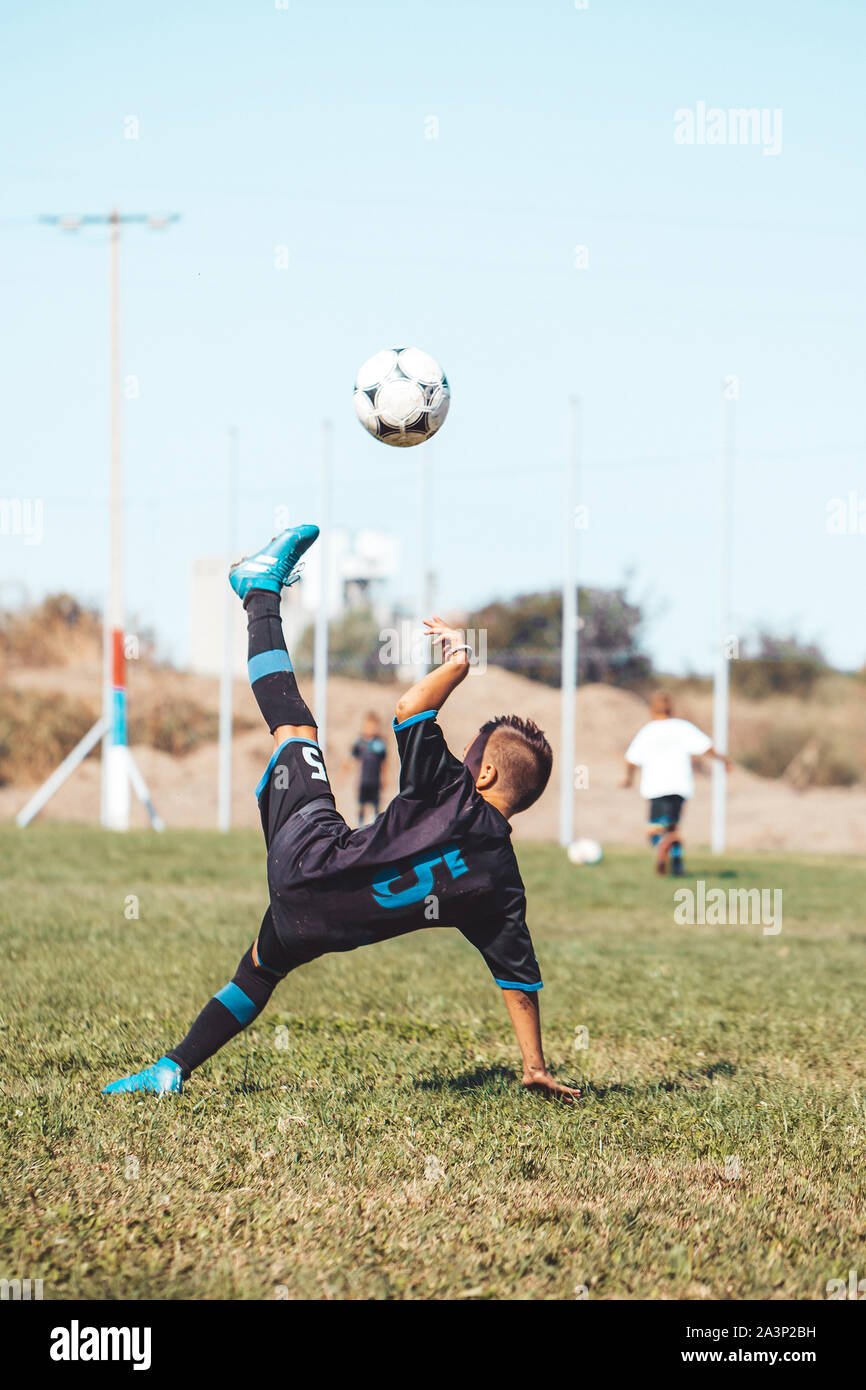 Little boy with soccer ball doing flying kick at stadium. Kid soccer