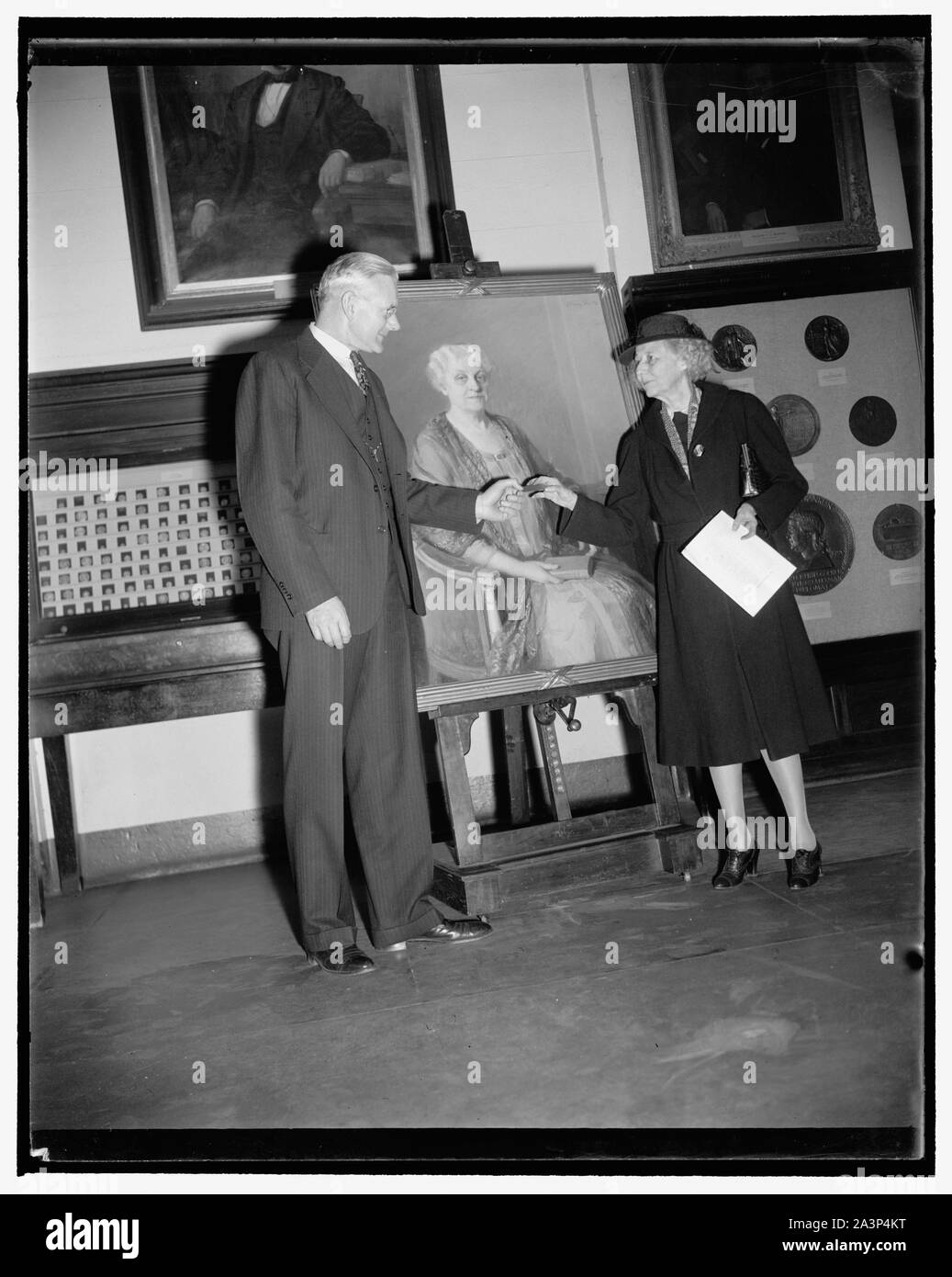 Smithsonian receives portrait of famed suffrage leader. Washington, D.C., Nov. 17. Miss Marguerite H. Welles, President of the National League of Women Voters, presenting to Dr. Alexander Wetmore, Assistant Secretary of the Smithsonian Institution, an oil painting of 80 year old Carrie Chapman Catt. The portrait will be hung in the Smithsonian Institution with the ones of three other famed suffrage leaders: Susan B. Anthony, Elizabeth Cady Stanton, and Dr. Anna Howard Shaw. A gift of Mrs. Stanley McCormick of Chicago, the portrait was painted by Mary Foote in 1927 Stock Photo