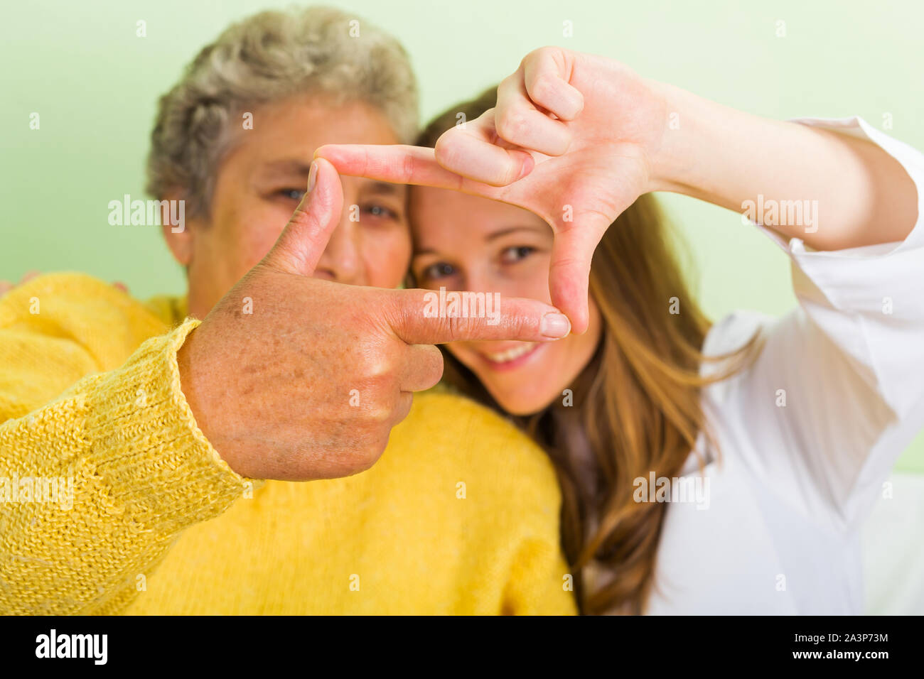 Elderly woman and her daughter make frame with their fingers Stock Photo