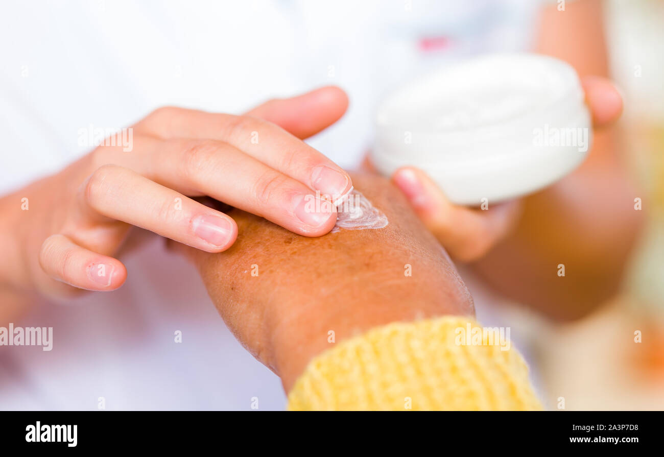 The carer rubbing the elderly woman's hand  with cream Stock Photo