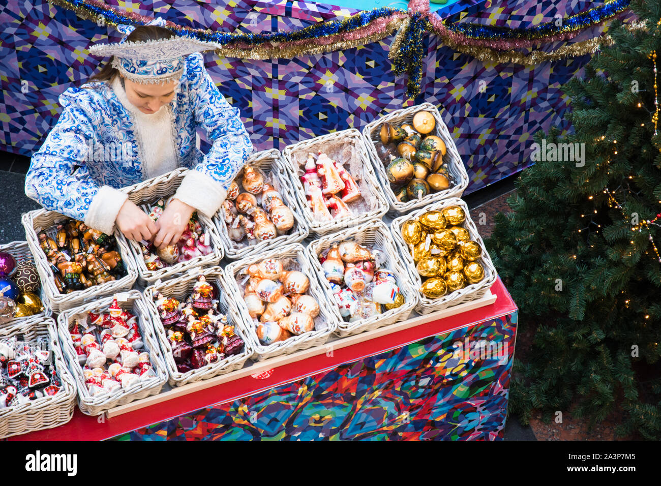 RUSSIA - MOSCOW. 28.12.2018. Christmas market in GUM. Girl in national outfit snow maiden sells holiday decorations to Christmas tree. View from above Stock Photo