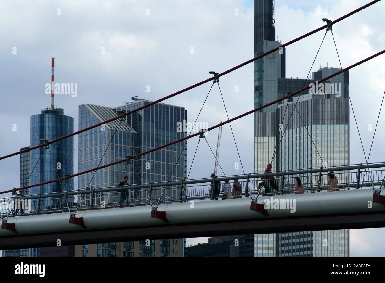 Frankfurt, Germany - August 03, 2019: Pedestrians walk across the modern bridge Holbeinsteg with skyscrapers of the financial district in the backgrou Stock Photo
