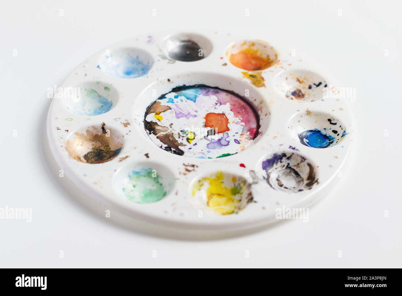 Artist palette full of dried coloured paint, isolated on a white background with a shallow depth of field Stock Photo