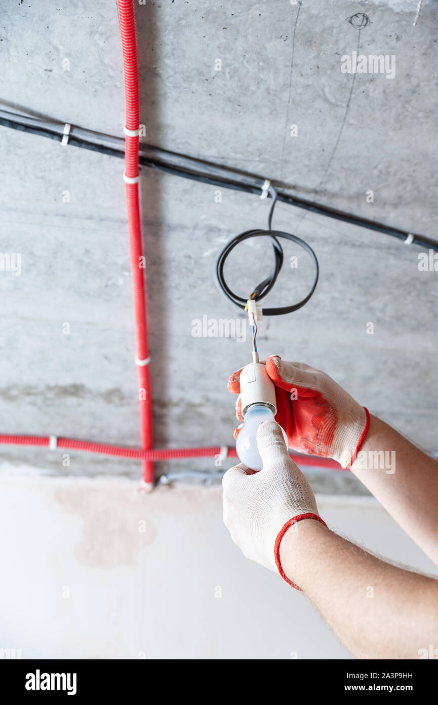 An electrician is setting a light bulb for temporary lighting. Stock Photo