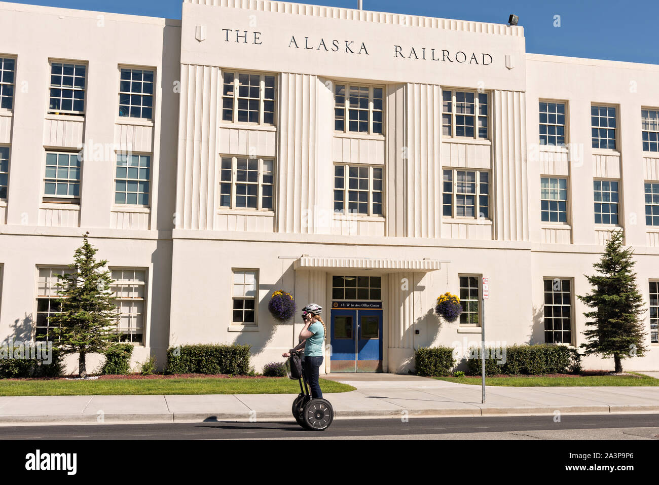 A woman rides a Segway past the Alaska Railroad depot in downtown