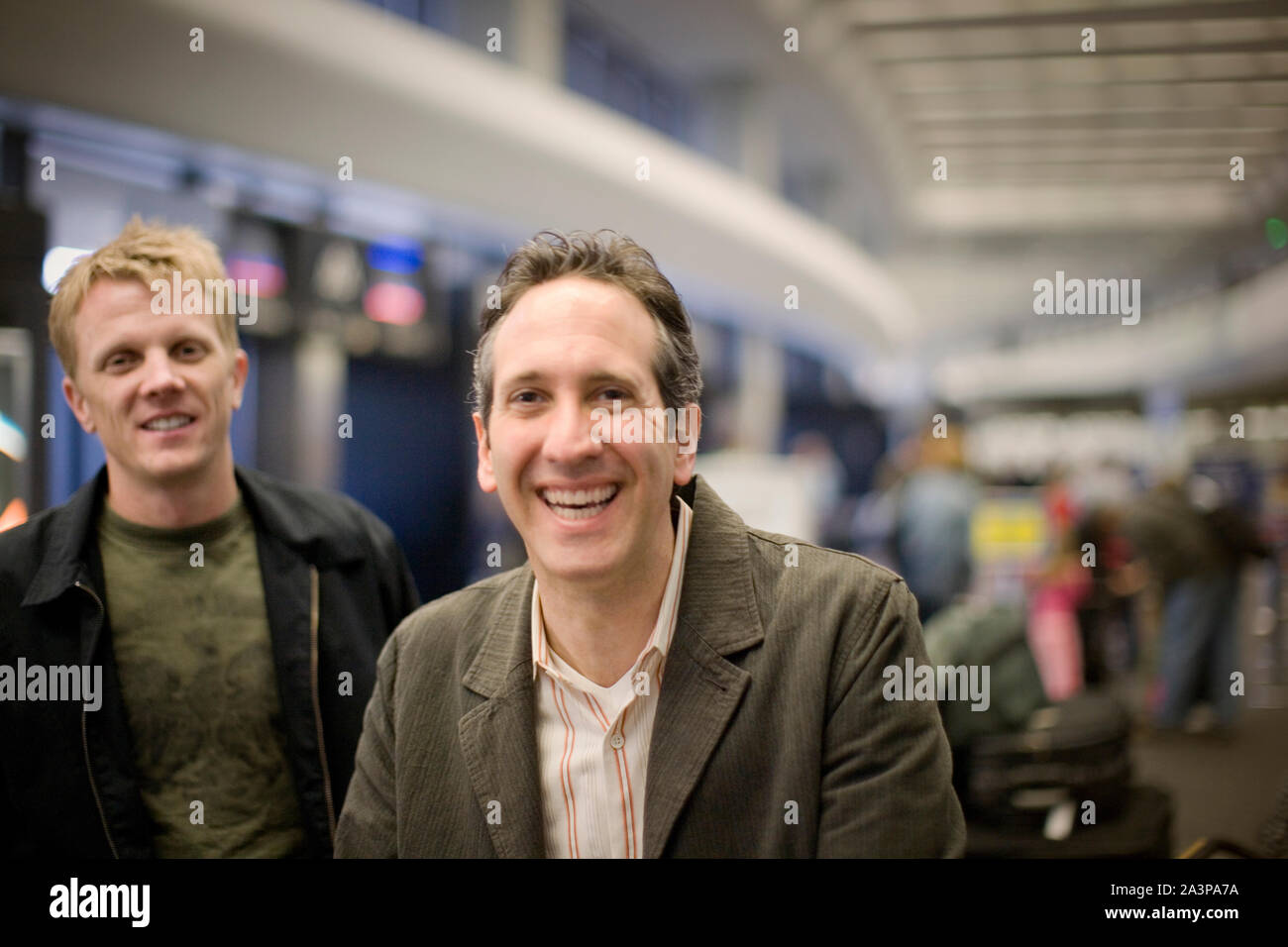 Portrait of two smiling mid-adult men inside an airport. Stock Photo